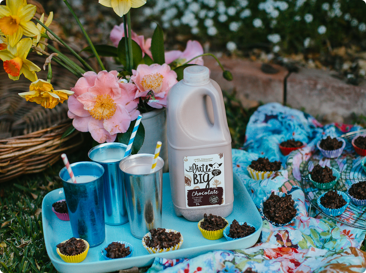 Chocolate milk outside next to a vase of flowers and milkshakes.